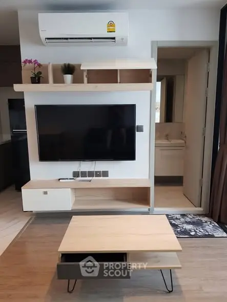 Modern living room with wall-mounted TV and air conditioning, featuring sleek wooden furniture and open layout.