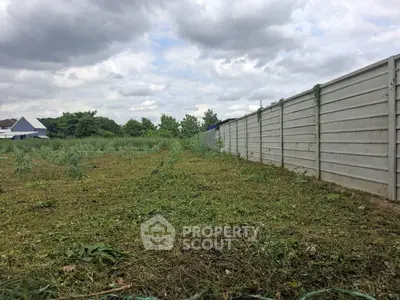 Spacious vacant land with lush greenery and privacy fence, ideal for development opportunities.