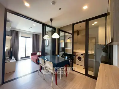 Modern open-plan living room with dining area and kitchen, featuring stylish decor and natural light.