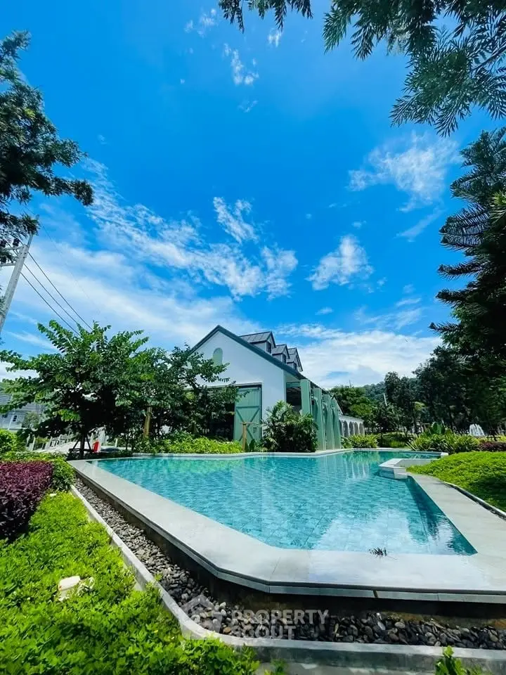 Stunning poolside view of a modern house with lush greenery and clear blue sky.