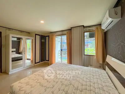 Spacious bedroom with large windows and modern decor in a stylish apartment.