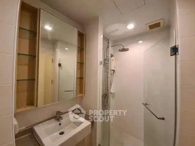 Modern bathroom with glass shower and sleek vanity in a contemporary apartment.