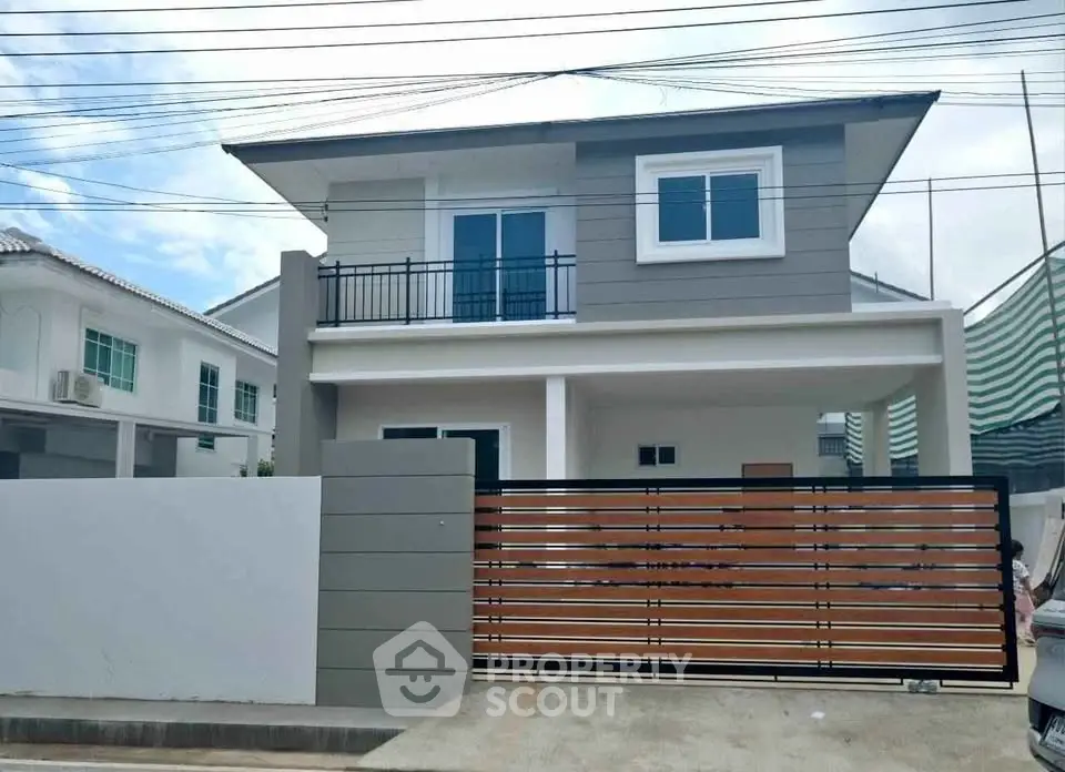 Modern two-story house with sleek design and gated entrance in suburban neighborhood.