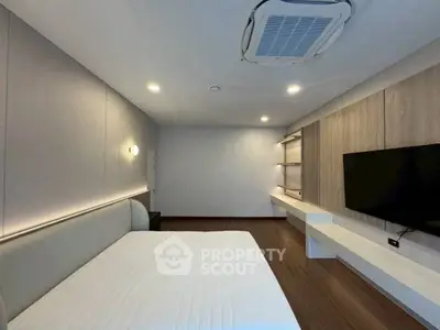 Modern bedroom with sleek design, featuring a wall-mounted TV and stylish lighting.