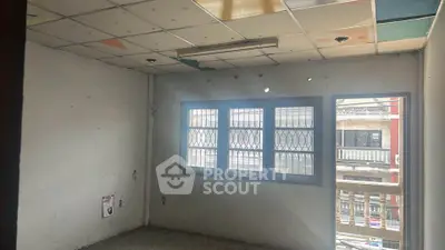 Spacious room with large window and balcony access in urban setting