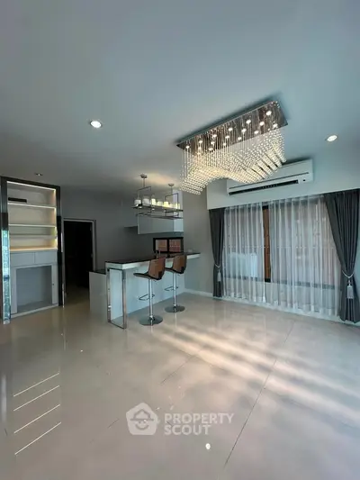 Luxurious modern living room with elegant chandelier and sleek bar area