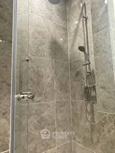 Luxurious marble-tiled shower with modern fixtures in a sleek bathroom.