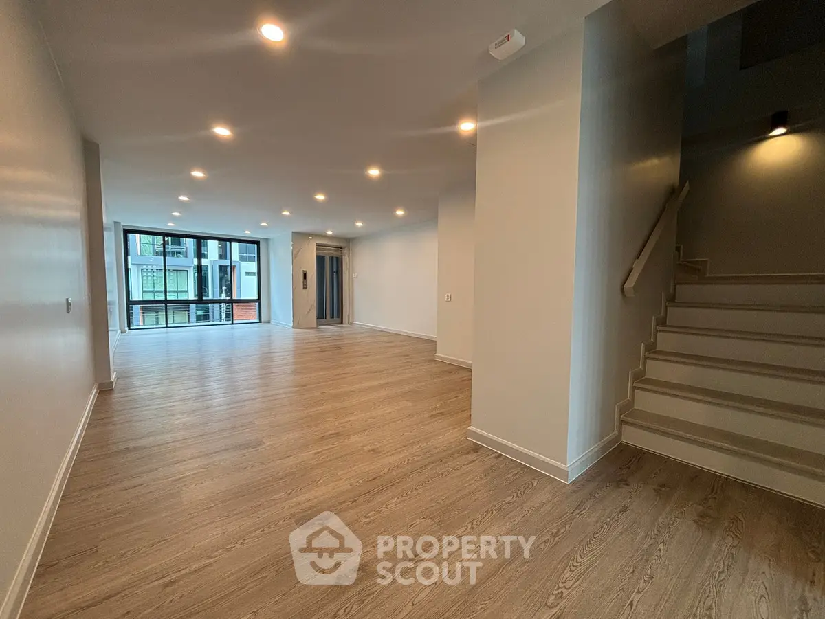 Spacious modern living room with wooden flooring and ample natural light