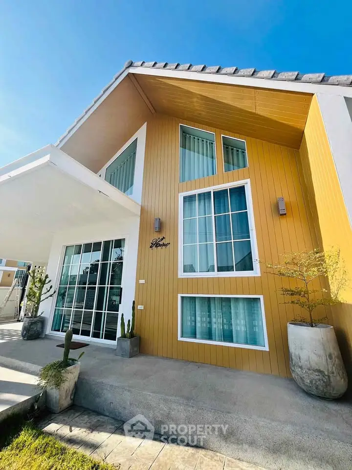 Charming modern house exterior with large windows and stylish facade under clear blue sky.