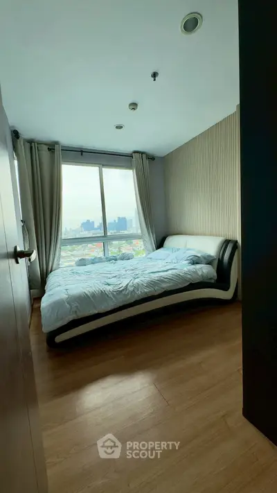 Modern bedroom with city view and stylish bed in high-rise apartment.