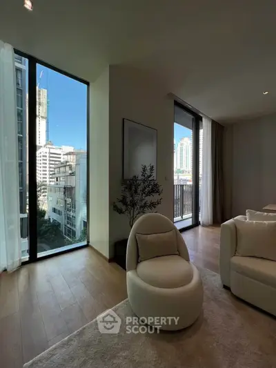 Modern living room with floor-to-ceiling windows and city view, featuring elegant furniture and natural light.