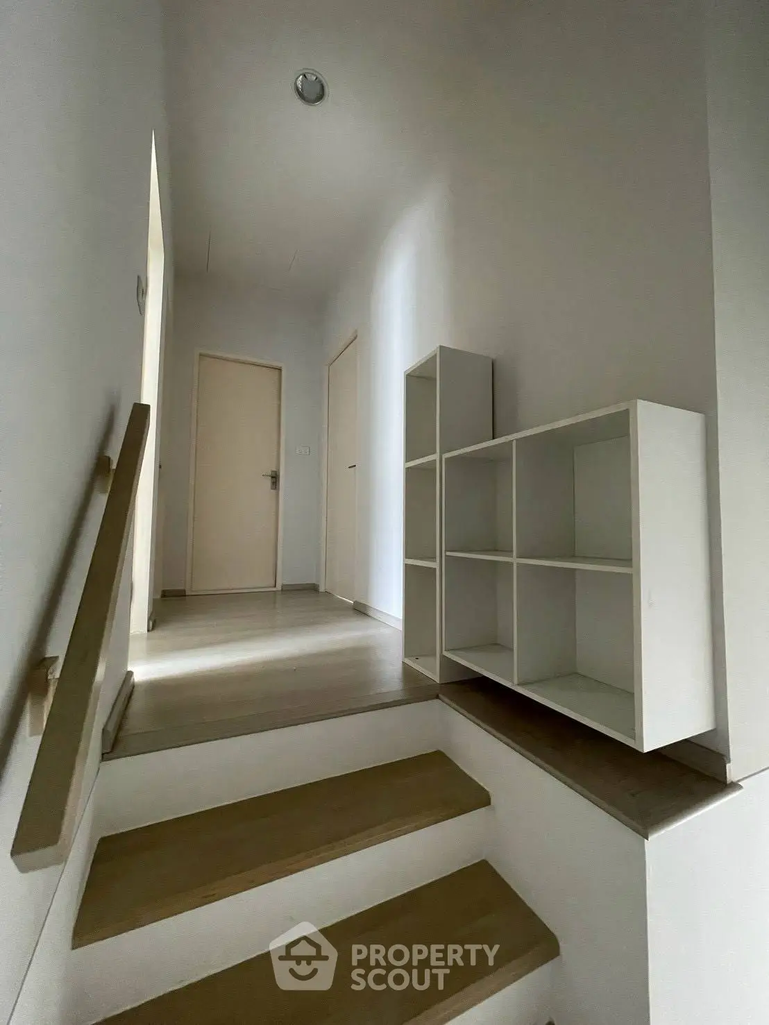 Modern minimalist hallway with wooden stairs and white shelving unit
