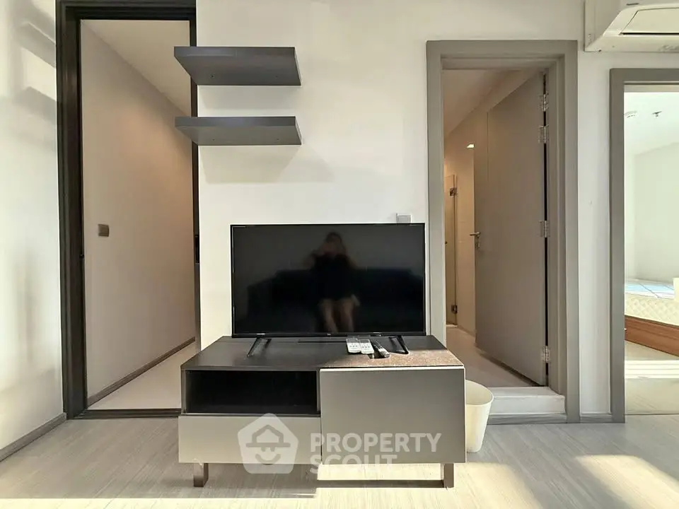 Modern living room with sleek TV stand and floating shelves in a bright apartment