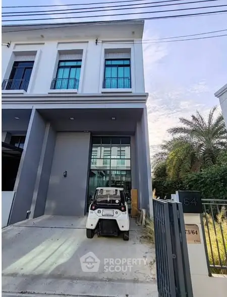 Modern townhouse with sleek facade and small electric vehicle parked in driveway