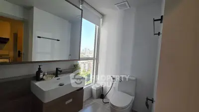 Modern bathroom with city view, featuring sleek fixtures and natural light.