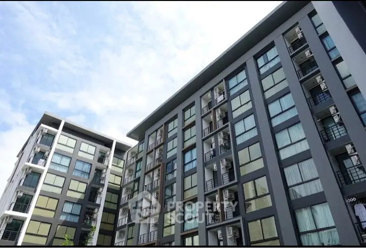 Modern apartment building with sleek design and large windows under a clear blue sky.