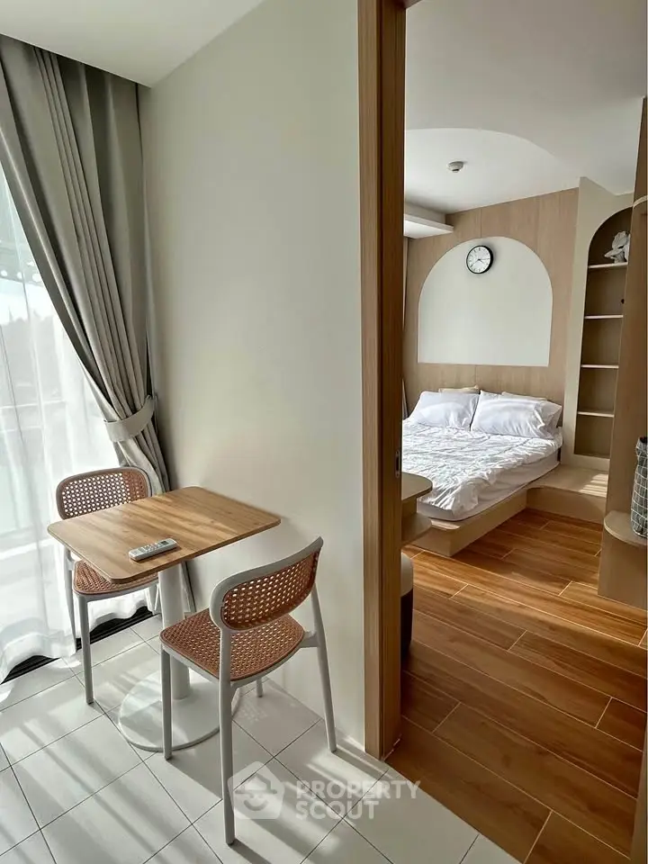 Cozy bedroom with wooden flooring and small dining area, perfect for modern living.