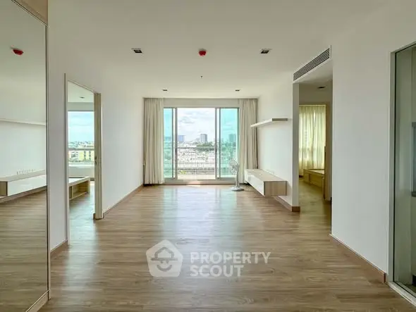 Spacious modern living room with large windows and wooden flooring, offering a bright and airy atmosphere.