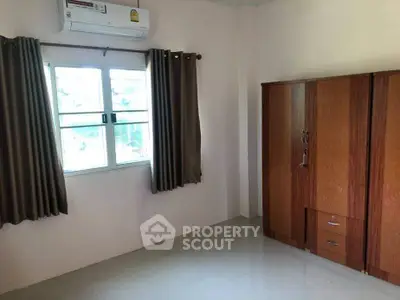 Spacious bedroom with air conditioning and wooden wardrobe, perfect for comfortable living.