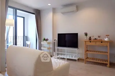 Modern living room with balcony access, featuring a sleek TV setup and stylish furniture.