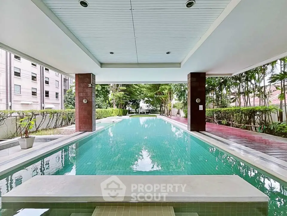 Luxurious condominium pool with lush greenery and modern design, perfect for relaxation and leisure.