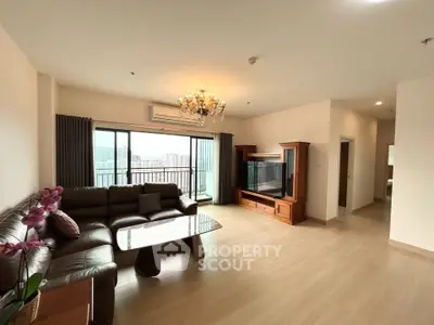 Spacious living room with elegant chandelier and city view balcony in modern apartment.