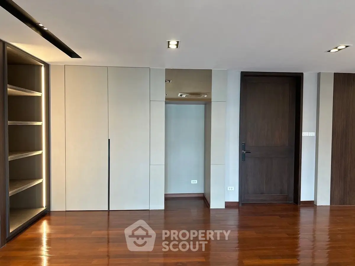 Spacious modern interior with wooden flooring and built-in shelving, ideal for stylish living.
