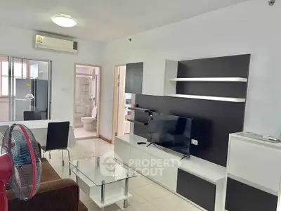 Modern living room with sleek furniture and open layout, featuring a TV and dining area.