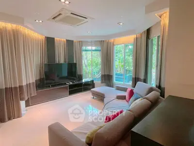 Spacious living room with modern decor and large windows offering lush garden views.