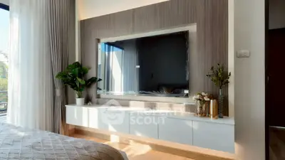 Modern bedroom with elegant decor and large wall-mounted TV