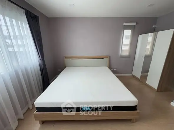 Spacious bedroom with modern decor and large windows for natural light.