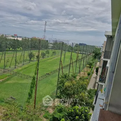 Scenic view from balcony overlooking lush green golf course and city skyline.