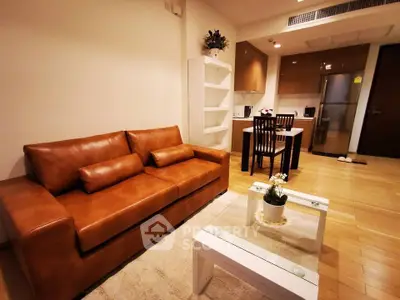 Cozy living room with leather sofa and modern kitchen in open layout apartment.