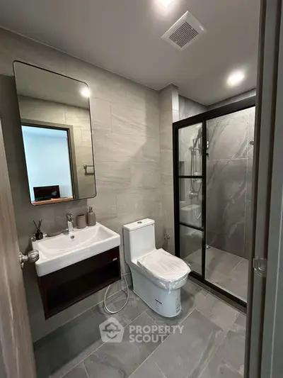 Modern bathroom with sleek design, featuring a glass shower enclosure and contemporary fixtures.