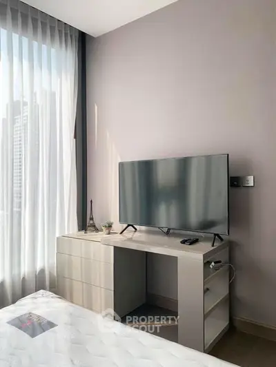 Modern bedroom with sleek TV setup and city view through large window.