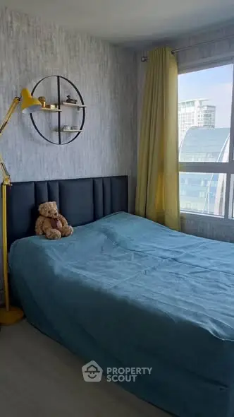 Cozy bedroom with modern decor and large window offering city views, featuring a stylish bed and unique lighting.