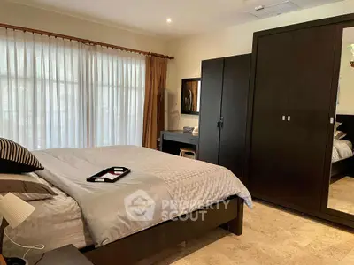 Spacious bedroom with modern furniture and large window for natural light.