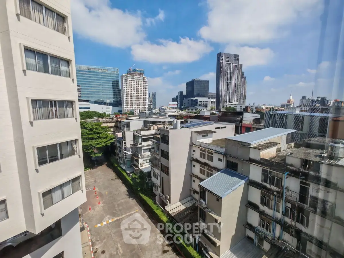 Stunning cityscape view from high-rise apartment with modern buildings and clear blue sky.