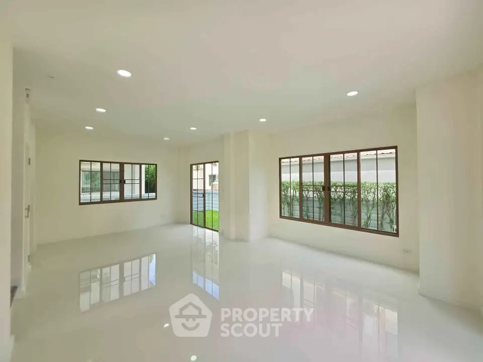 Spacious and bright living room with large windows and glossy floors in modern home.