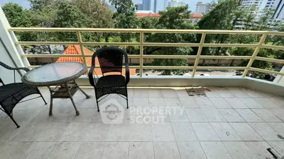 Spacious balcony with outdoor seating and scenic view of lush greenery.