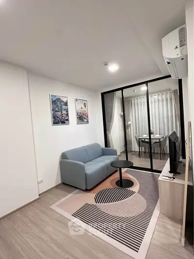 Modern living room with stylish decor and glass partition leading to dining area.