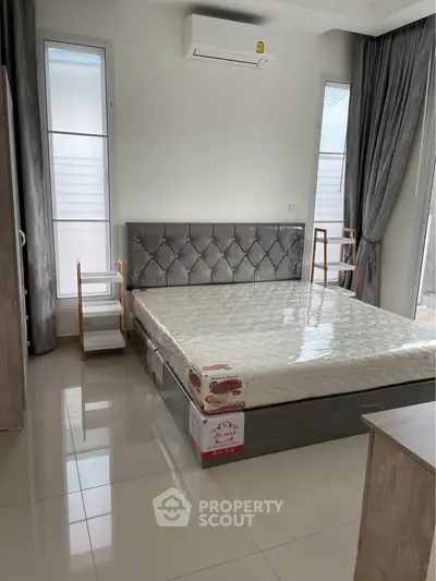Modern bedroom with stylish bed and air conditioning in a bright, elegant setting.