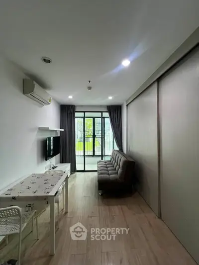 Modern living room with sleek design, featuring a cozy sofa, wall-mounted TV, and large windows opening to a balcony.
