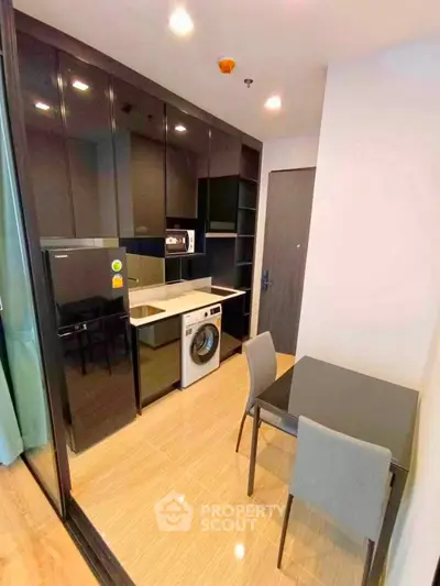 Modern kitchen with sleek black cabinets, integrated appliances, and cozy dining area.