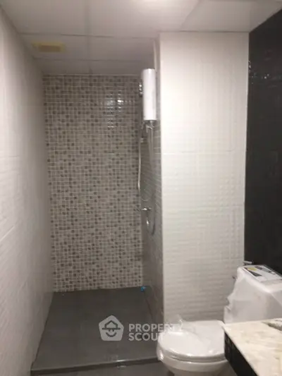 Modern bathroom with sleek tile design and shower area in contemporary apartment.