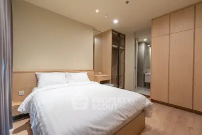 Modern bedroom with wooden flooring, built-in wardrobe, and ensuite bathroom in a stylish apartment.