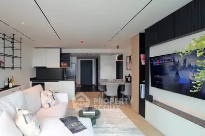 Modern open-layout living room with sleek design and large TV, perfect for entertainment and relaxation.