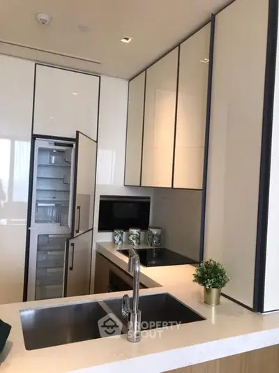 Modern kitchen with sleek cabinetry and built-in appliances, featuring a double sink and minimalist design.
