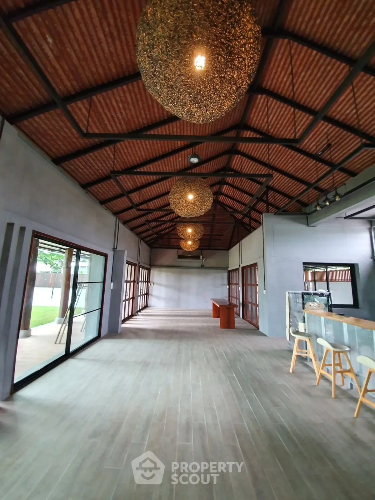 Spacious open-plan living area with modern design and high ceilings, featuring stylish lighting and large windows.