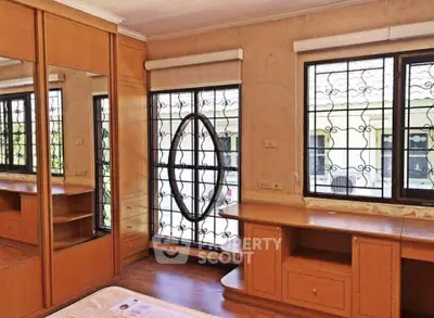 Spacious bedroom with large windows and built-in wooden furniture